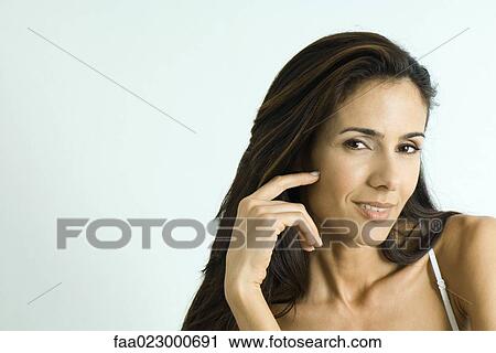 Woman touching cheek, smiling at camera, portrait View Large Photo Image Stock Image - Woman touching cheek, smiling at camera, portrait. Fotosearch