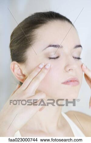 Picture - Woman touching cheeks, eyes closed, head and shoulders. Fotosearch