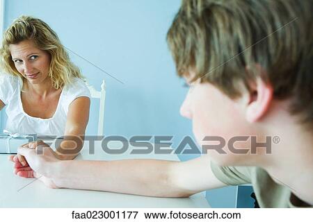 Woman with present looking at teen son, holding his hand View Large Photo Image Stock Photo - Woman with present looking at teen son, holding his hand. Fotosearch