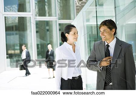 Young business associates standing together, chatting, smiling View Large Photo Image Picture - Young business associates standing together, chatting, smiling. Fotosearch