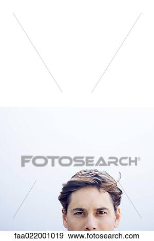 Stock Photo - Young businessman looking at camera, cropped view of head. Fotosearch