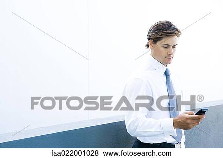 Young businessman looking at cell phone, waist up View Large Photo Image Stock Photo - Young businessman looking at cell phone, waist up. Fotosearch