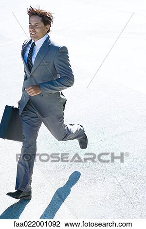 Young businessman running outdoors, carrying briefcase, full length View Large Photo Image Stock Image - Young businessman running outdoors, carrying briefcase, full length. Fotosearch