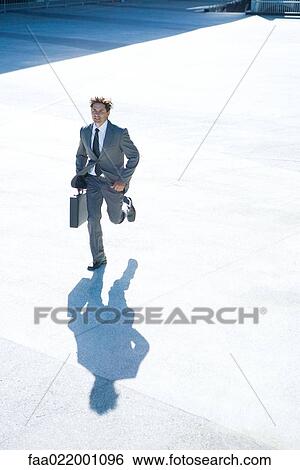Young businessman running outdoors, carrying briefcase, full length View Large Photo Image Stock Photograph - Young businessman running outdoors, carrying briefcase, full length. Fotosearch