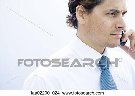 Picture - Young businessman using cell phone, side view. Fotosearch