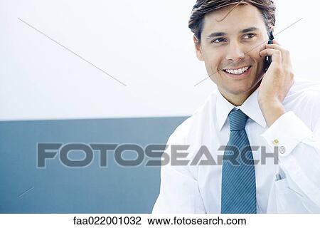 Young businessman using cell phone, smiling, looking away View Large Photo Image Stock Image - Young businessman using cell phone, smiling, looking away. Fotosearch
