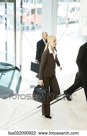 Young businesswoman entering lobby, carrying briefcase, man in background View Large Photo Image Stock Image - Young businesswoman entering lobby, carrying briefcase, man in background. Fotosearch