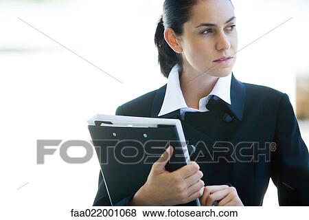 Young businesswoman holding binder, looking away View Large Photo Image Stock Photo - Young businesswoman holding binder, looking away. Fotosearch