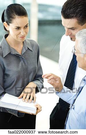 Young businesswoman holding file, chatting with male associates View Large Photo Image Stock Photo - Young businesswoman holding file, chatting with male associates. Fotosearch