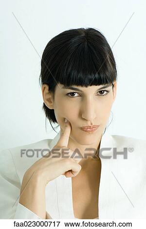Young businesswoman, holding finger to cheek, looking at camera, portrait View Large Photo Image Stock Photo - Young businesswoman, holding finger to cheek, looking at camera, portrait. Fotosearch
