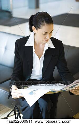 Young businesswoman sitting on couch, reading newspaper View Large Photo Image Stock Image - Young businesswoman sitting on couch, reading newspaper. Fotosearch