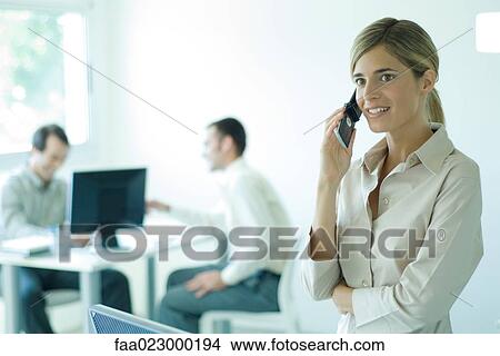 Young businesswoman using cell phone in office, waist up View Large Photo Image Picture - Young businesswoman using cell phone in office, waist up. Fotosearch