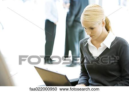 Young businesswoman using laptop computer, looking down, waist up View Large Photo Image Stock Image - Young businesswoman using laptop computer, looking down, waist up. Fotosearch