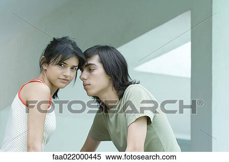 Stock Photography - Young couple, female looking at camera while male looks at her. Fotosearch