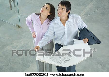 Young couple holding blueprints, looking up, high angle view View Large Photo Image Stock Image - Young couple holding blueprints, looking up, high angle view. Fotosearch