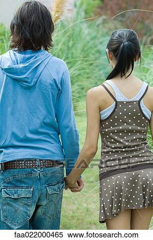 Stock Photography - Young couple holding hands, rear view. Fotosearch