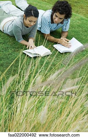 Young couple lying on grass reading books View Large Photo Image Stock Image - Young couple lying on grass reading books. Fotosearch