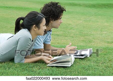 Young couple lying on grass with books, looking out of frame View Large Photo Image Stock Image - Young couple lying on grass with books, looking out of frame. Fotosearch