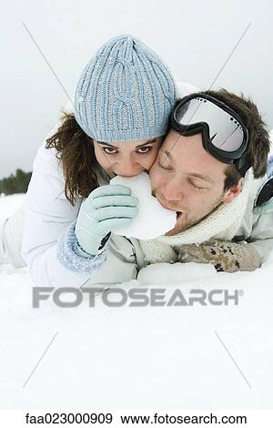 Young couple lying on the ground together, eating snow, female smiling at camera View Large Photo Image Stock Photo - Young couple lying on the ground together, eating snow, female smiling at camera. Fotosearch