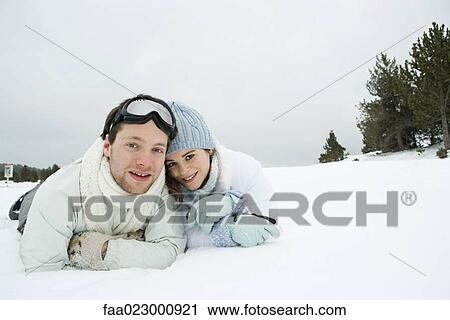 Young couple lying side by side in snow, smiling at camera, portrait View Large Photo Image Stock Image - Young couple lying side by side in snow, smiling at camera, portrait. Fotosearch