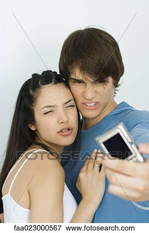Stock Photo - Young couple making faces at digital camera together. Fotosearch