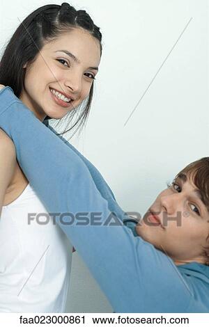 Young couple, man reaching up to put arms around woman's neck, portrait View Large Photo Image Stock Image - Young couple, man reaching up to put arms around woman's neck, portrait. Fotosearch
