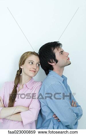 Young couple, man turning back to young woman, arms crossed, waist up, portrait View Large Photo Image Stock Photo - Young couple, man turning back to young woman, arms crossed, waist up, portrait. Fotosearch