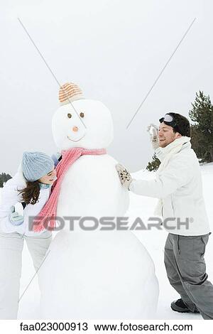 Young couple peeking around snowman at each other, holding up snowballs View Large Photo Image Stock Image - Young couple peeking around snowman at each other, holding up snowballs. Fotosearch