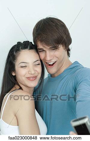 Young couple posing for photo, man holding out digital camera, portrait View Large Photo Image Stock Photo - Young couple posing for photo, man holding out digital camera, portrait. Fotosearch