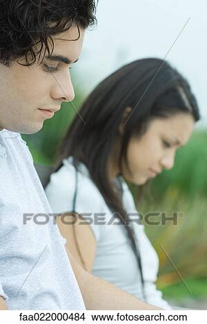 Young couple reading, cropped view, focus on man in foreground View Large Photo Image Picture - Young couple reading, cropped view, focus on man in foreground. Fotosearch