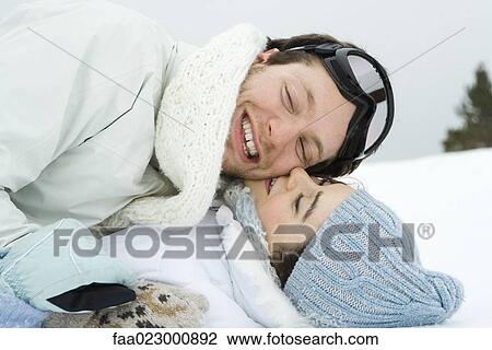 Young couple reclining in snow together, smiling, eyes closed, one on top of the other View Large Photo Image Stock Image - Young couple reclining in snow together, smiling, eyes closed, one on top of the other. Fotosearch