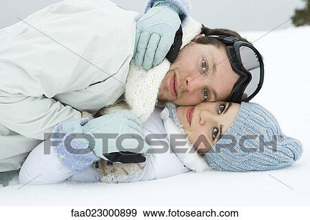 Stock Photo - Young couple reclining on the ground together, cheek to cheek, embracing, smiling at camera. Fotosearch