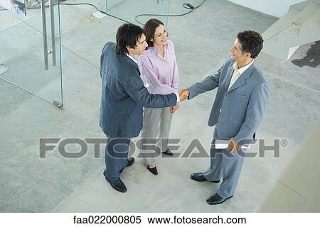 Young couple shaking hands with real estate agent, high angle view View Large Photo Image Stock Photography - Young couple shaking hands with real estate agent, high angle view. Fotosearch