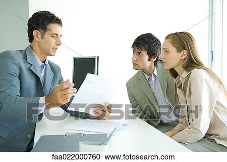 Young couple sitting across desk from businessman, businessman explaining document View Large Photo Image Stock Image - Young couple sitting across desk from businessman, businessman explaining document. Fotosearch