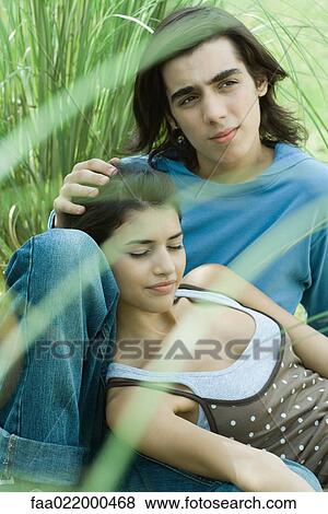 Young couple sitting in grass, woman leaning head against boyfriend's knee View Large Photo Image Stock Photo - Young couple sitting in grass, woman leaning head against boyfriend's knee. Fotosearch