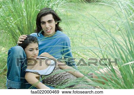 Young couple sitting in grass, woman leaning head against boyfriend's knee View Large Photo Image Stock Photo - Young couple sitting in grass, woman leaning head against boyfriend's knee. Fotosearch