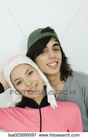 Young couple smiling at camera together, both wearing hats, cheek to cheek, portrait View Large Photo Image Stock Photo - Young couple smiling at camera together, both wearing hats, cheek to cheek, portrait. Fotosearch