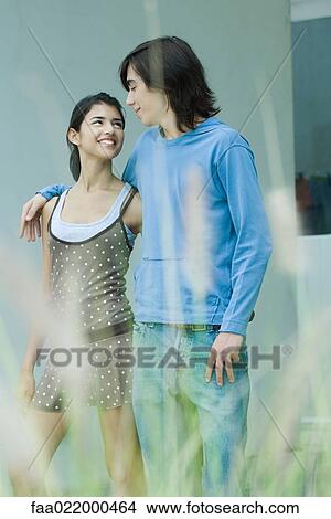 Young couple, smiling at each other, focus on background View Large Photo Image Picture - Young couple, smiling at each other, focus on background. Fotosearch
