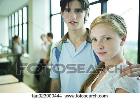 Picture - Young couple standing in college library, looking at camera, portrait. Fotosearch