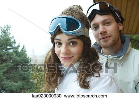 Stock Image - Young couple standing together, smiling at camera, portrait. Fotosearch