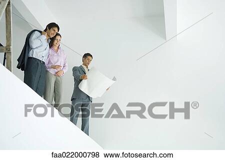 Young couple standing with architect, looking over unfinished interior, low angle view View Large Photo Image Stock Photo - Young couple standing with architect, looking over unfinished interior, low angle view. Fotosearch