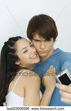 Young couple taking self portrait with digital camera, woman smiling, man furrowing brow View Large Photo Image Stock Photograph - Young couple taking self portrait with digital camera, woman smiling, man furrowing brow. Fotosearch