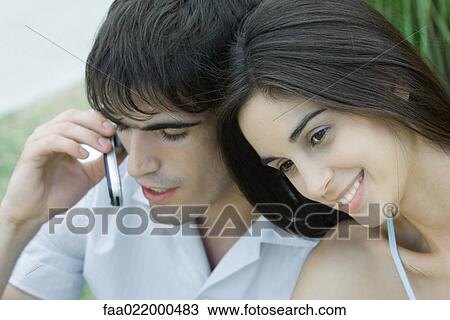 Young couple, woman leaning head against man while man uses cell phone, head and shoulders, portrait View Large Photo Image Stock Image - Young couple, woman leaning head against man while man uses cell phone, head and shoulders, portrait. Fotosearch