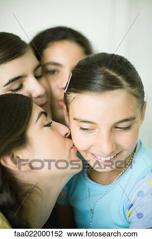 Young female friends kissing younger girl's cheek View Large Photo Image Stock Image - Young female friends kissing younger girl's cheek. Fotosearch