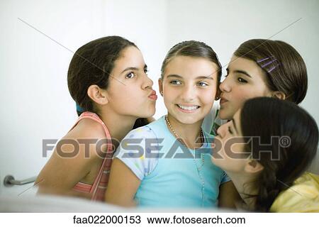 Stock Image - Young female friends kissing younger girl's cheeks. Fotosearch