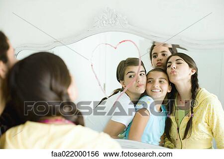 Young female friends looking at mirror, puckering View Large Photo Image Stock Photograph - Young female friends looking at mirror, puckering. Fotosearch