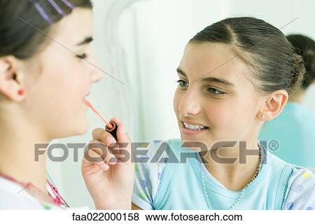 Young female friends putting make-up on each other View Large Photo Image Stock Photo - Young female friends putting make-up on each other. Fotosearch