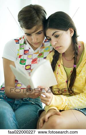 Young female friends reading book together View Large Photo Image Stock Photo - Young female friends reading book together. Fotosearch