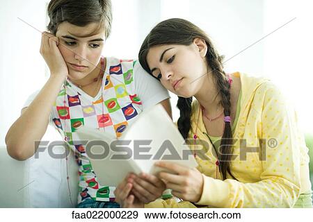 Young female friends reading book together View Large Photo Image Stock Photo - Young female friends reading book together. Fotosearch