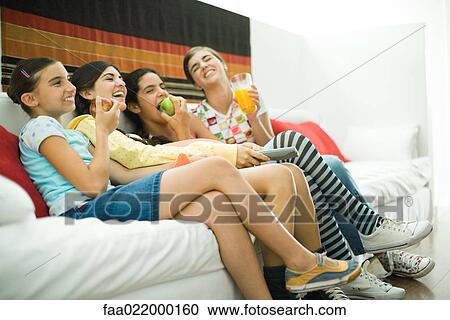 Young female friends sitting on sofa, eating healthy snacks together View Large Photo Image Stock Image - Young female friends sitting on sofa, eating healthy snacks together. Fotosearch